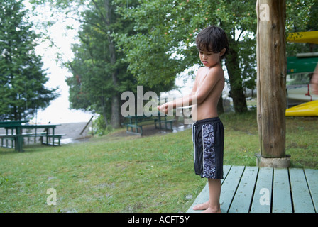 Kleiner Junge in Badeanzug warten auf Regen zu stoppen Stockfoto