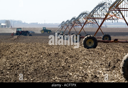 Bewässerungssystem im Vordergrund mit Traktoren im Hintergrund auf einem Bauernhof von Illinois im April 2007 Stockfoto