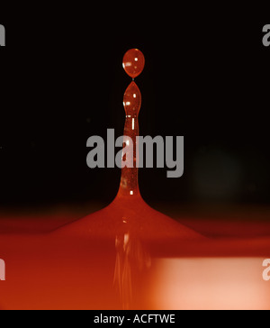 Eine Spalte Spritzer rot gefärbten Wasser oben zu brechen, wie es zurück fällt Stockfoto