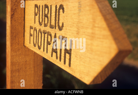 Nahaufnahme von einem hölzernen Wegweiser im warmen Abendlicht mit Rasen und track mit geätzten Worte öffentlichen Fußweg Stockfoto