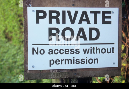 Schwarz / weiß-Schild an Telefonmast besagt Privatstraße kein Zugang ohne Erlaubnis und mit Hecke hinter Stockfoto