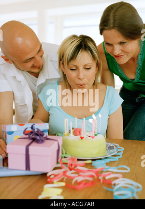 Eine Frau Ausblasen der Kerzen auf einem Geburtstagskuchen. Stockfoto