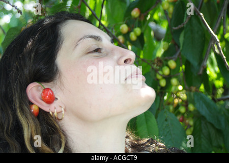 Junge Frau lächelt und paar Kirsche auf ihr Ohr tragen Stockfoto