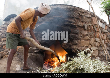 Indischer Mann feuert Tontöpfe in eine äußere Brennofen in der Stadt Puttaparthi, Andhra Pradesh, Indien Stockfoto