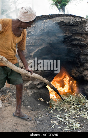 Indischer Mann feuert Tontöpfe in eine äußere Brennofen in der Stadt Puttaparthi, Andhra Pradesh, Indien Stockfoto