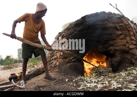 Indischer Mann feuert Tontöpfe in eine äußere Brennofen in der Stadt Puttaparthi, Andhra Pradesh, Indien Stockfoto