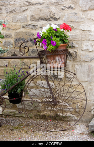 Dekorative Blume Fahrradkorb außerhalb einer Ladenfront in den Cotswolds Stadt Burford, England Stockfoto