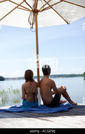 Ein paar sitzt auf einer Brücke unter einem Sonnenschirm Rückansicht. Stockfoto