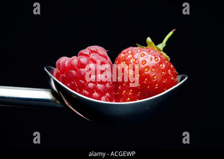 Himbeere und Erdbeere in einem Löffel Schaufel auf schwarzem Hintergrund Stockfoto