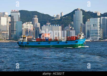 Schiff, beladen mit Containern im Victoria Harbour mit Skyline Hong Kong SAR Stockfoto