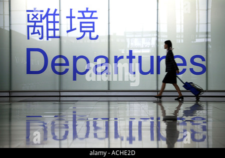 Abflugschild des Flughafens Hong Kong mit Passagier, der vorbeikommt Stockfoto