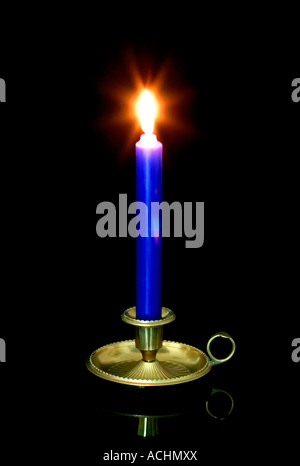 Blaue Kerze brennt in einem Messing-Halter Stockfoto