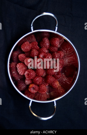 Silberne Schale voller Himbeeren, vor schwarzem Hintergrund Stockfoto