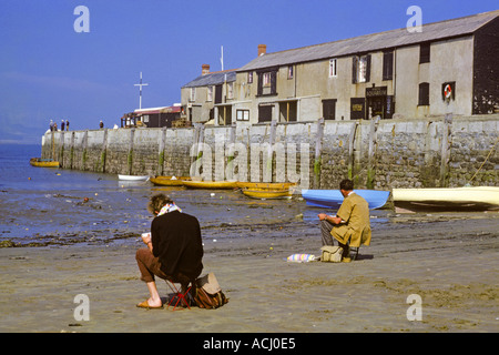 England Lyme Regis Dorset zwei Künstler am Strand bei Ebbe mit Booten und Cobb im Hintergrund JMH0369 Stockfoto