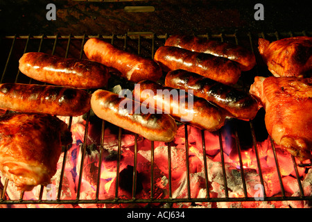 Würstchen und Chicken auf einem Grill in der Nacht. Stockfoto