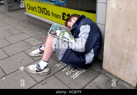 Ein Big Issue Verkäufer schlafend auf seinem Stellplatz außerhalb einen Plattenladen HMV in Western Road Brighton Stockfoto