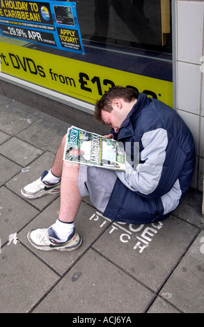 Ein Big Issue Verkäufer schlafend auf seinem Stellplatz außerhalb einen Plattenladen HMV in Western Road Brighton Stockfoto