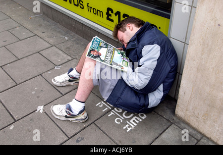 Ein Big Issue Verkäufer schlafend auf seinem Stellplatz außerhalb einen Plattenladen HMV in Western Road Brighton Stockfoto