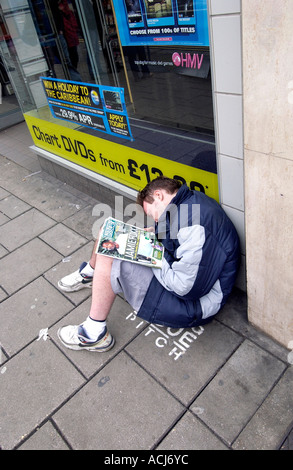 Ein Big Issue Verkäufer schlafend auf seinem Stellplatz außerhalb einen Plattenladen HMV in Western Road Brighton Stockfoto