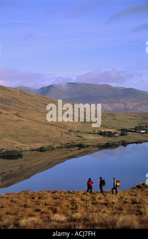 Wanderer über Lough Gebühr an die Maumturk Mountains, Connemara, County Galway, Irland. Stockfoto