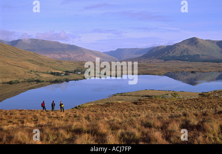 Wanderer über Lough Gebühr an die Maumturk Mountains, Connemara, County Galway, Irland. Stockfoto