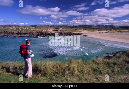Wanderer über einen Sandstrand am Ufer des Mannin Bay, Connemara, County Galway, Irland. Stockfoto