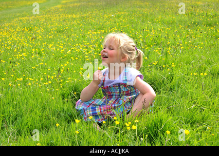 Junges Mädchen saß in Wiese von Butterblumen Stockfoto