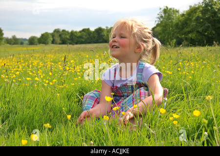 Junges Mädchen saß in Wiese von Butterblumen Stockfoto