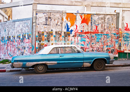 Ein Klassiker, aber heruntergekommenen blau-weiße alte amerikanische Auto geparkt in einer Straße in der Stadt vor dem Hintergrund einer Wand voller politischer und Werbung Plakate Montevideo, Uruguay, Südamerika Stockfoto
