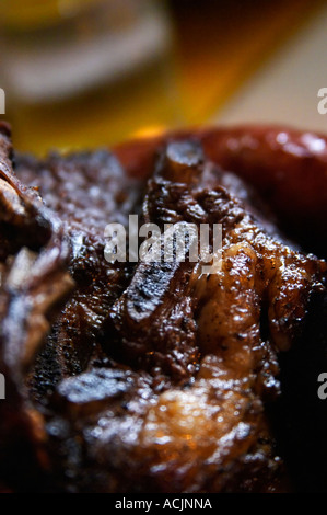 Eine Schüssel mit typischen Uruguay Grill mit Huhn, Schweinefleisch, Rindfleisch, Würstchen, Kalbsbries, Blutwürste und mehr in einem Restaurant entlang der Küste in Montevideo. Nahaufnahme von ein Stück gebratene Rippe Schweinefleisch Spare Rippen Spareribs im Restaurant La Portland auf der Wasserseite Montevideo, Uruguay, Südamerika Stockfoto