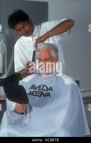 Senioren kaukasischen Mann bekommt Haarschnitt von malaysischen Barber im Friseurladen. Stockfoto