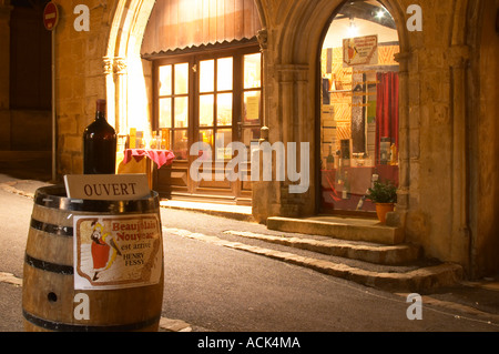 Ein Kopfsteinpflaster Straße in der Altstadt mit einer Weinhandlung. Bei Nacht. ein Weinfass auf der Straße Werbung Beaujolais Nouveau, Höhle Le Temps du Vin, rue des Fontaines Bergerac Dordogne Frankreich Stockfoto