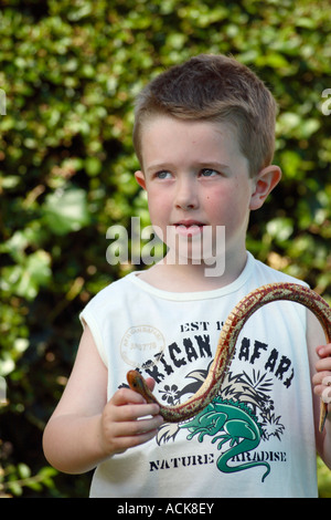 Ein kleiner Junge eine Spielzeug-Schlange hält. Stockfoto