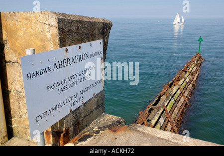 Wellenbrecher und Yacht am blauen Meer außerhalb Aberaeron Hafen Ceredigion West Wales UK GB Stockfoto