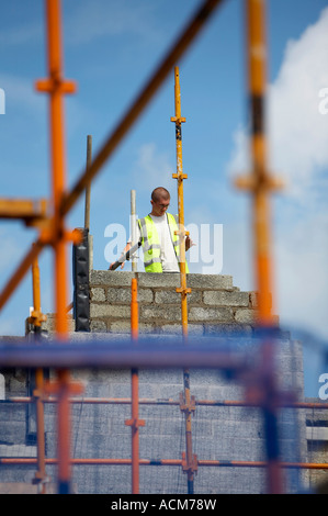 rasierte leitete jungen Mann mit Brille und hi-Vis Jacke aber kein Helm auf der Baustelle Stockfoto