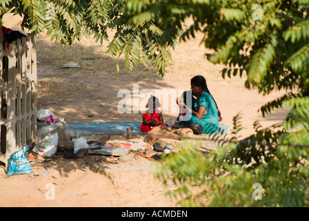 EINE ARBEITER-FRAU IST TAKING REST IM SCHATTEN EINES BAUMES ZUSAMMEN MIT IHRER TOCHTER KIND NACH HARTER ARBEIT Stockfoto