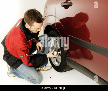 Junger Mann Reifendruck prüfen Stockfoto