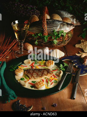 Gegrillten Wolfsbarsch mit Tri Farbe Paprika Artischockenherzen und Jakobsmuscheln in eine leichte pikante Creme Sauce serviert Stockfoto