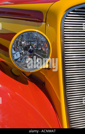 Vordere Scheinwerfer und Kühlergrill eines rot-gelb gestreiften Chevrolet Coupe Oldtimers auf einer Automesse Stockfoto