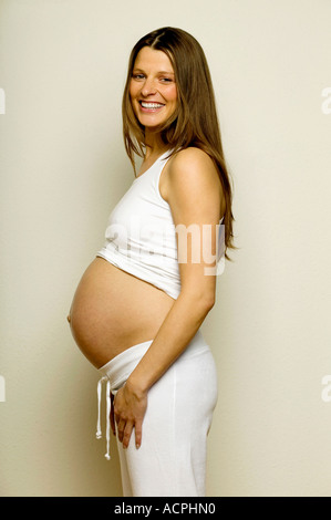 Schwangere Frau lächelnd, seitliche Ansicht Stockfoto