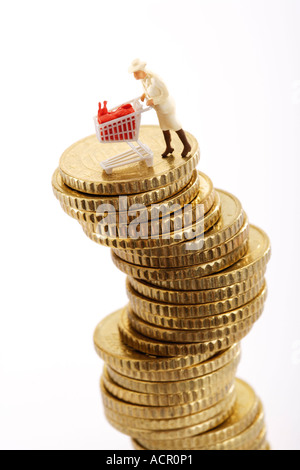 Figur mit Warenkorb auf Haufen von Münzen Stockfoto