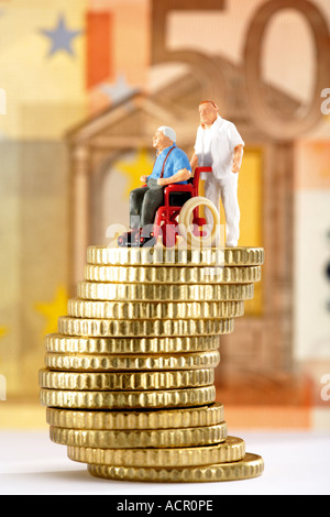 Figur im Rollstuhl und Betreuer auf Haufen von Münzen Stockfoto