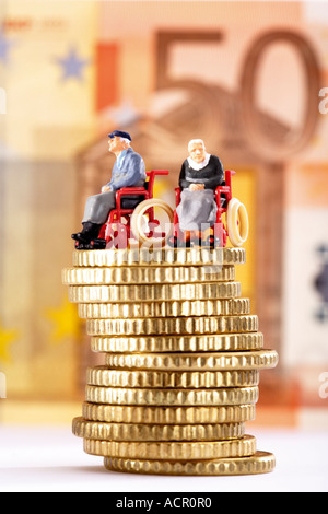 Figuren im Rollstuhl auf Haufen von Münzen Stockfoto