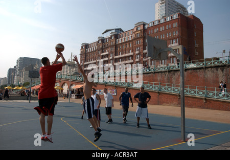 Basketball-Spieler auf dem freien Platz an Brighton Strandpromenade UK mit Hilton Metropole Hotel hinter Stockfoto