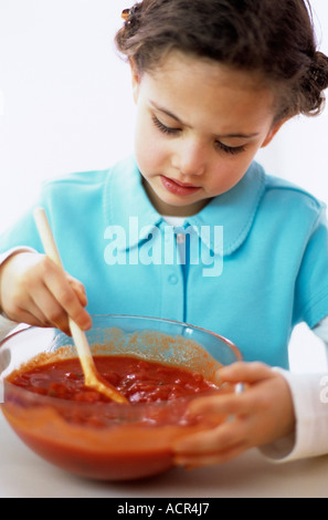 Mädchen (4-5) rühren Tomatensauce, close-up Stockfoto
