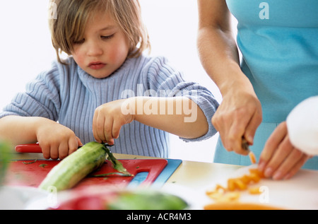 Sohn (4-7) und Mutter Schneiden von Gemüse, close-up Stockfoto