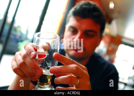 Mann hält ein Glas Bier in einem café Stockfoto