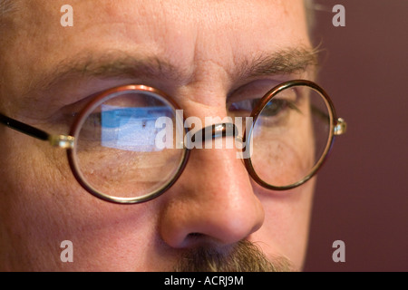 Ein Computer-Bildschirm reflektiert in einem schnauzbärtigen Mann runden Gläsern. Stockfoto