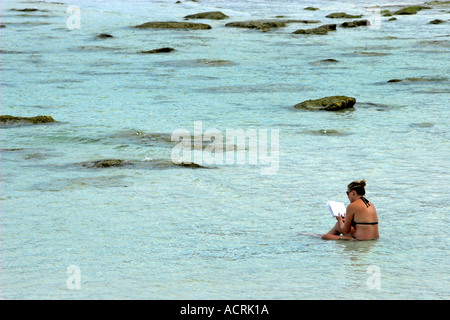 Junge Frau kühlt sich im Wasser am Strand lesen Buch Ko Pha Ngan Insel Thailand Stockfoto