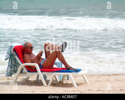 Mann liest Buch auf der Sonnenliege Patong Beach nach Tsunami Phuket Insel Thailand Stockfoto